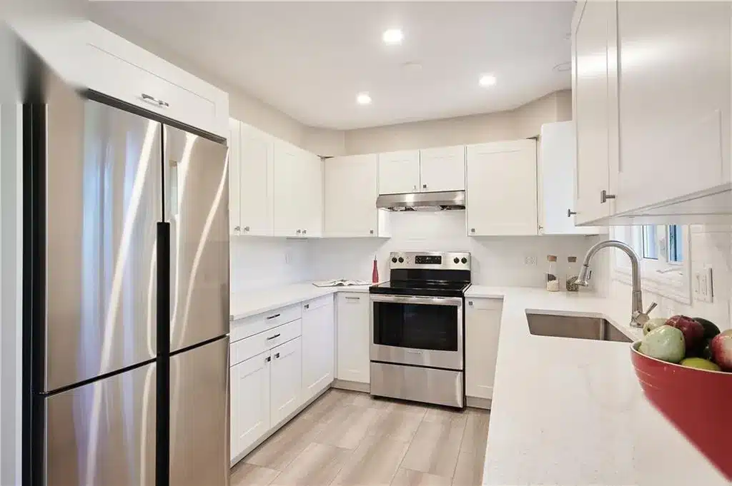 U-shaped IKEA AXSTAD matt white kitchen with quartz counters and stainless appliances